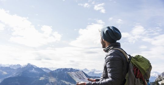 A man enjoying hiking in the mountains with a backpack and map.