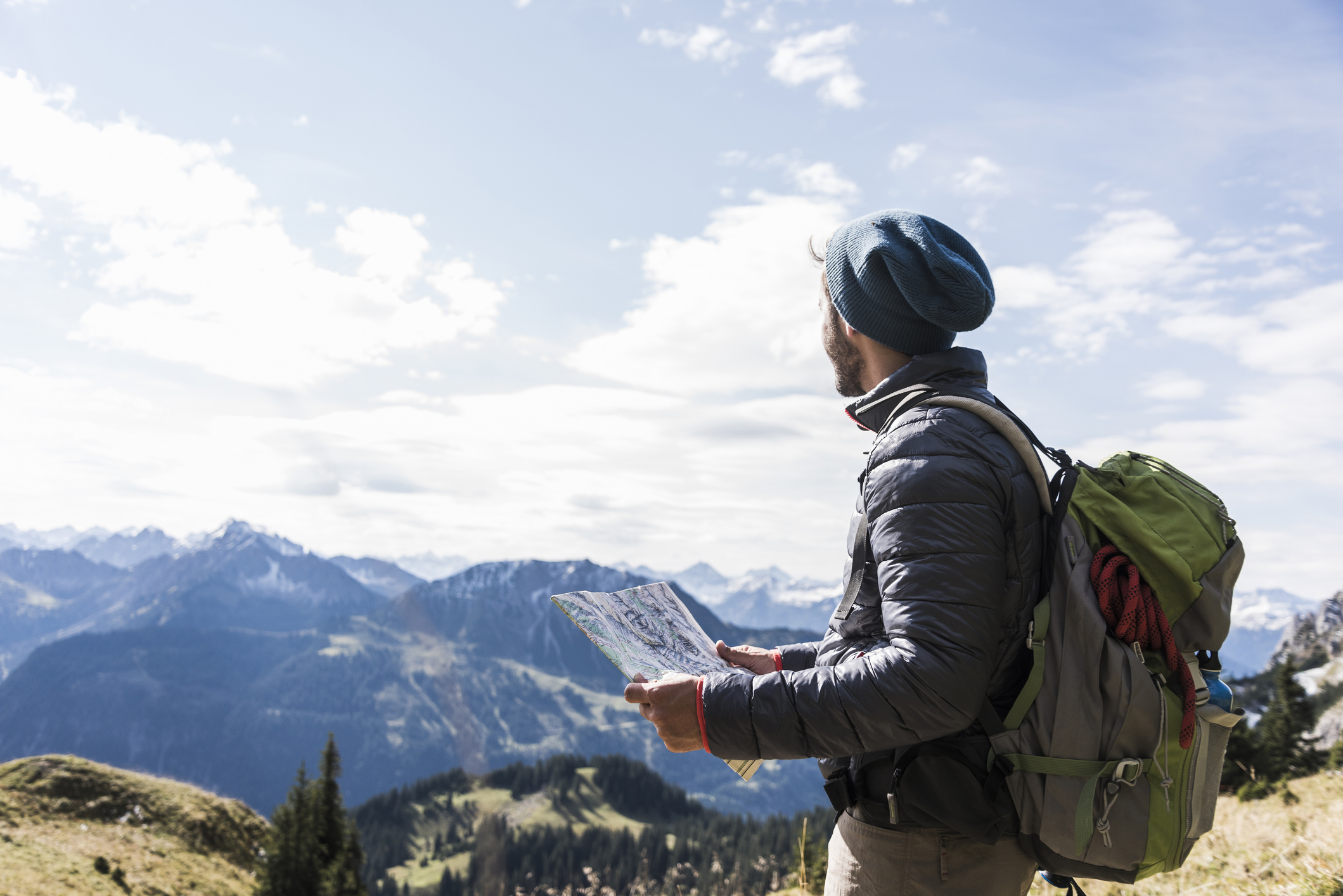 A man enjoying hiking in the mountains with a backpack and map.