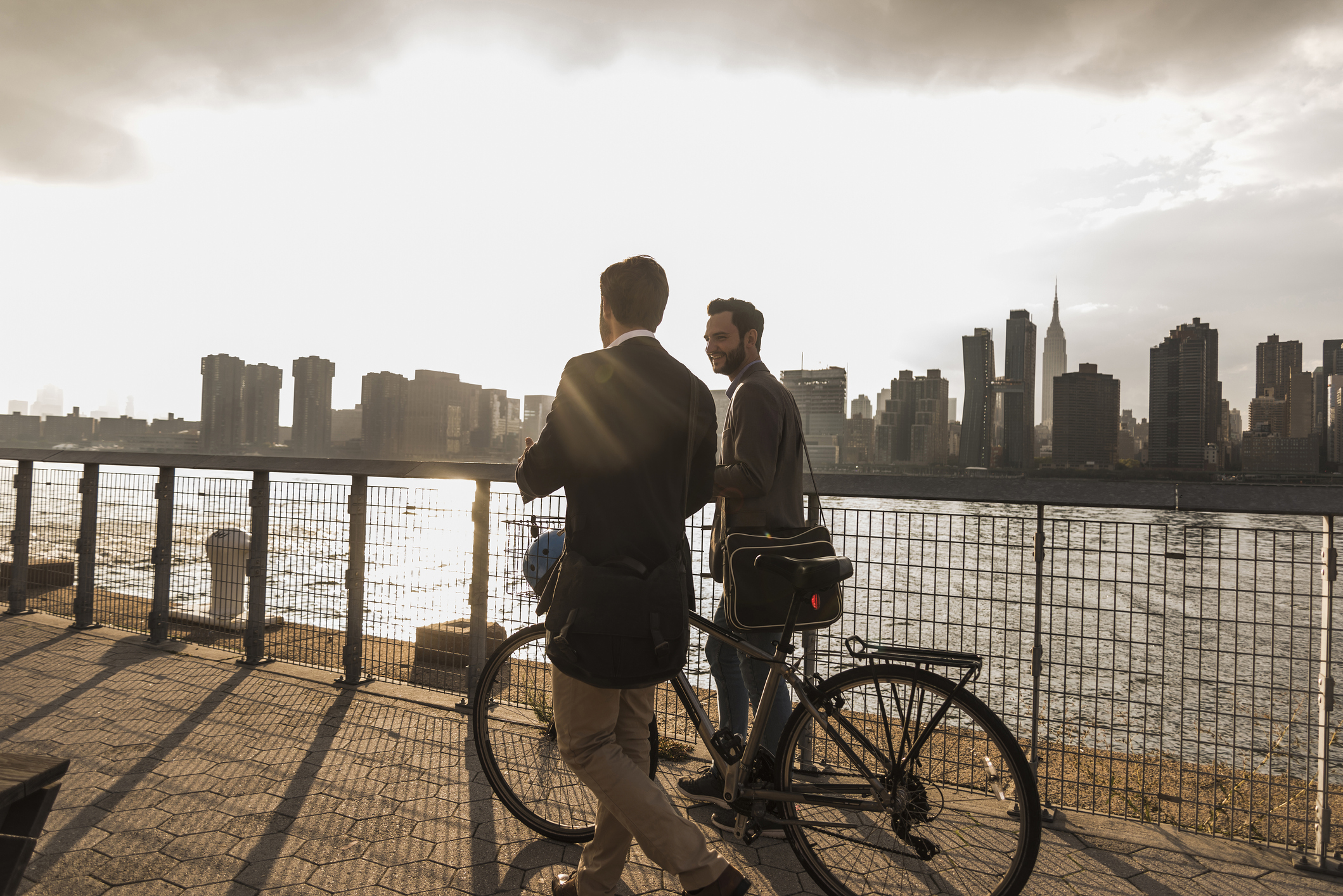 Two people standing next to a bike in front of a city.