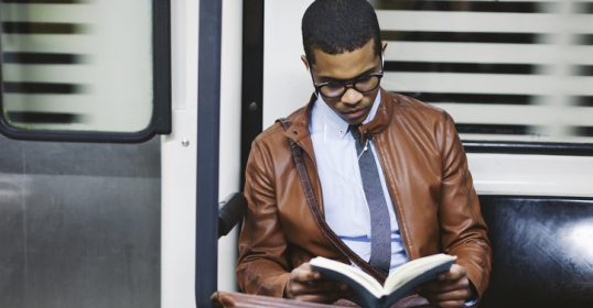 A man on a train reading a book.
