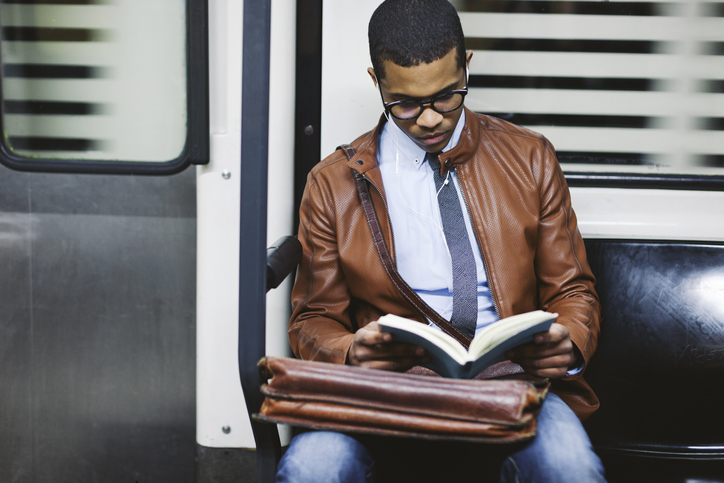 A man on a train reading a book.