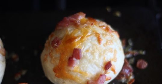 Bacon and cheese rolls on a baking sheet.