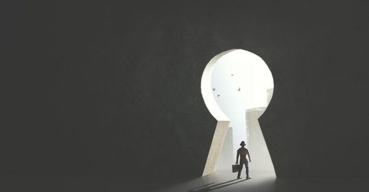 A businessman is navigating through a keyhole in a dark room, attempting to get out.