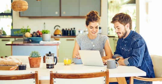 A man and woman sitting at a table using a laptop during a marriage meeting.