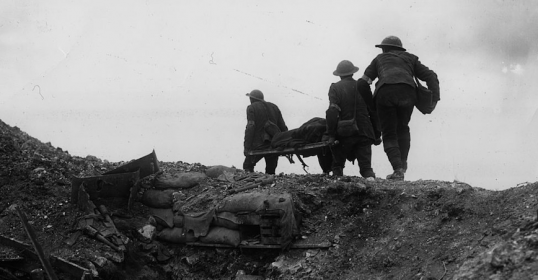 A group of soldiers standing on a hill near a trench, observing the battlefield.