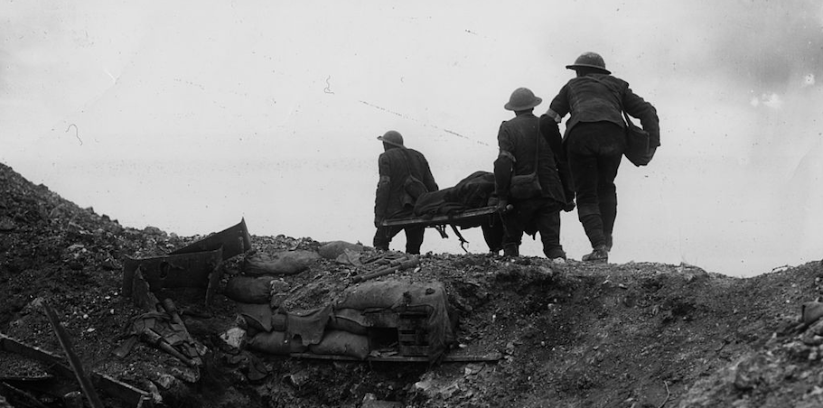 A group of soldiers standing on a hill near a trench, observing the battlefield.