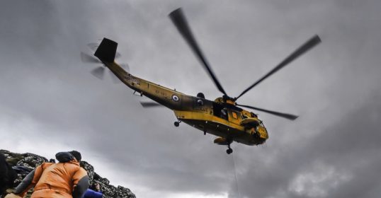Why is a helicopter hovering over a group of people on a mountain in survival situations?