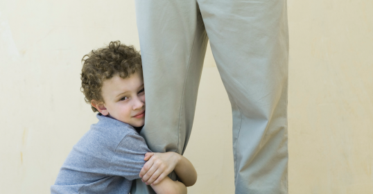 A young boy hugs his father's leg, offering comfort and security in moments of childhood anxiety.