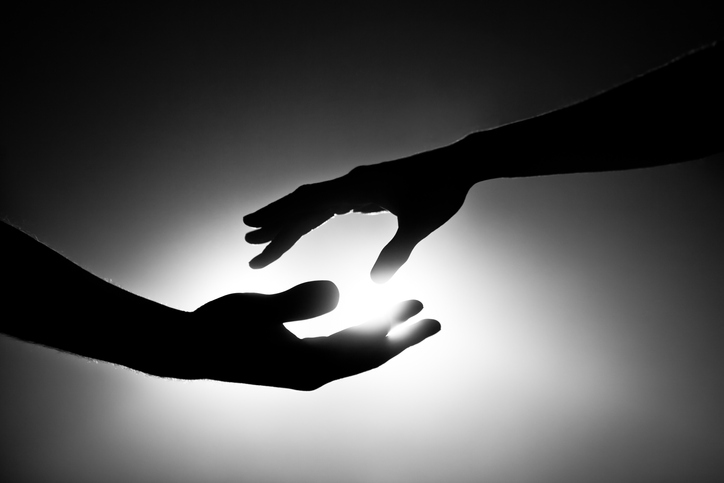 A silhouette of two hands reaching out, symbolizing connection in a lonely world.