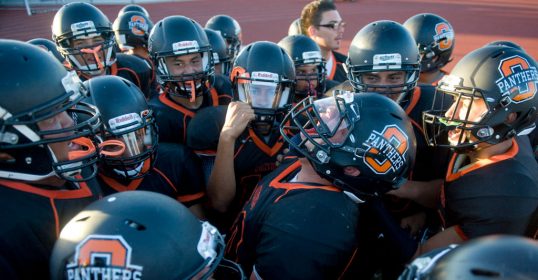 A group of boys in a huddle, preparing for the game with sportsmanship and ferocity.