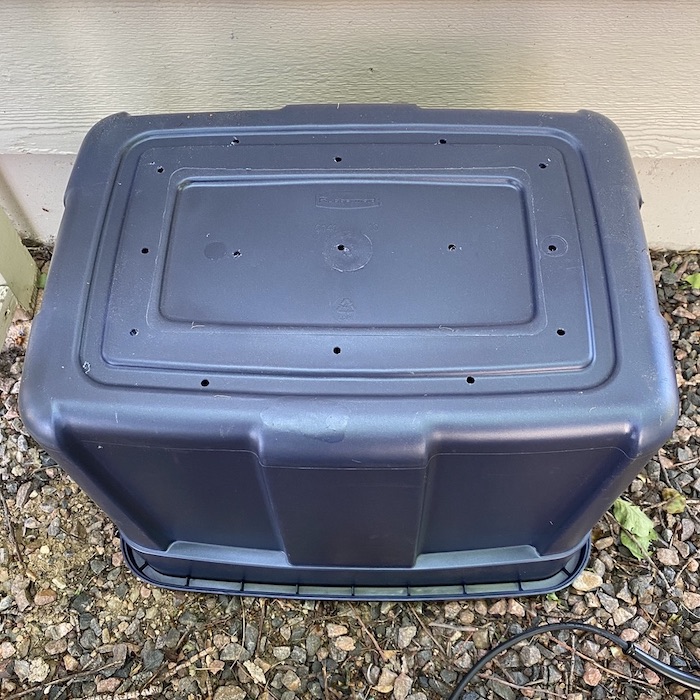 Several holes have been made in bin and it is placed upside down.