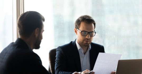 Two businessmen crafting a perfect cover letter at a table.