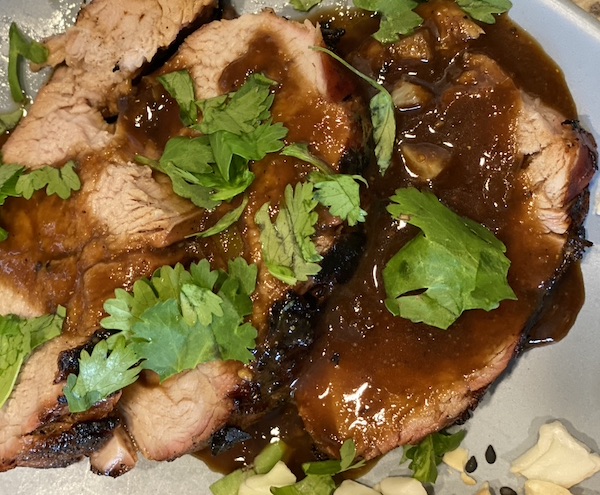 Peanut butter pork loin served with sauce with cilantro topping.