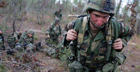 A soldier from army ranger school walking through the woods.