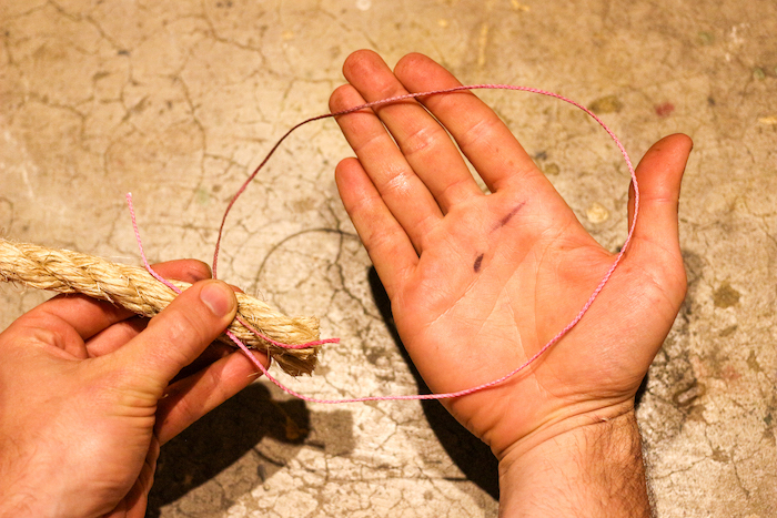 A man holding two ropes under thumb and loop in another hand. 