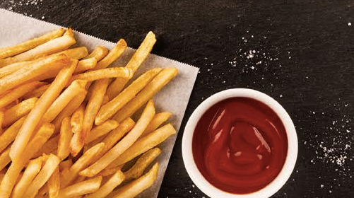 Leftover French fries and ketchup on a table.