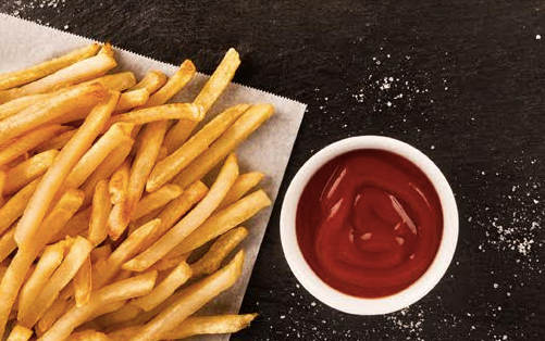Leftover French fries and ketchup on a table.