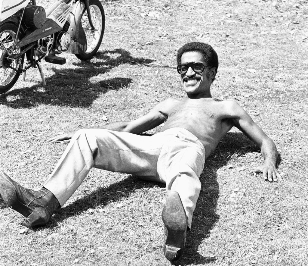 Smiling man laying along a bike.