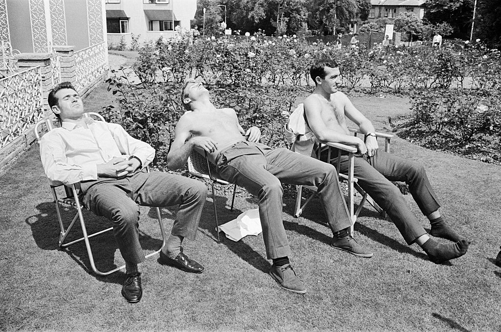 Three persons sitting on a chair and taking sunbath.