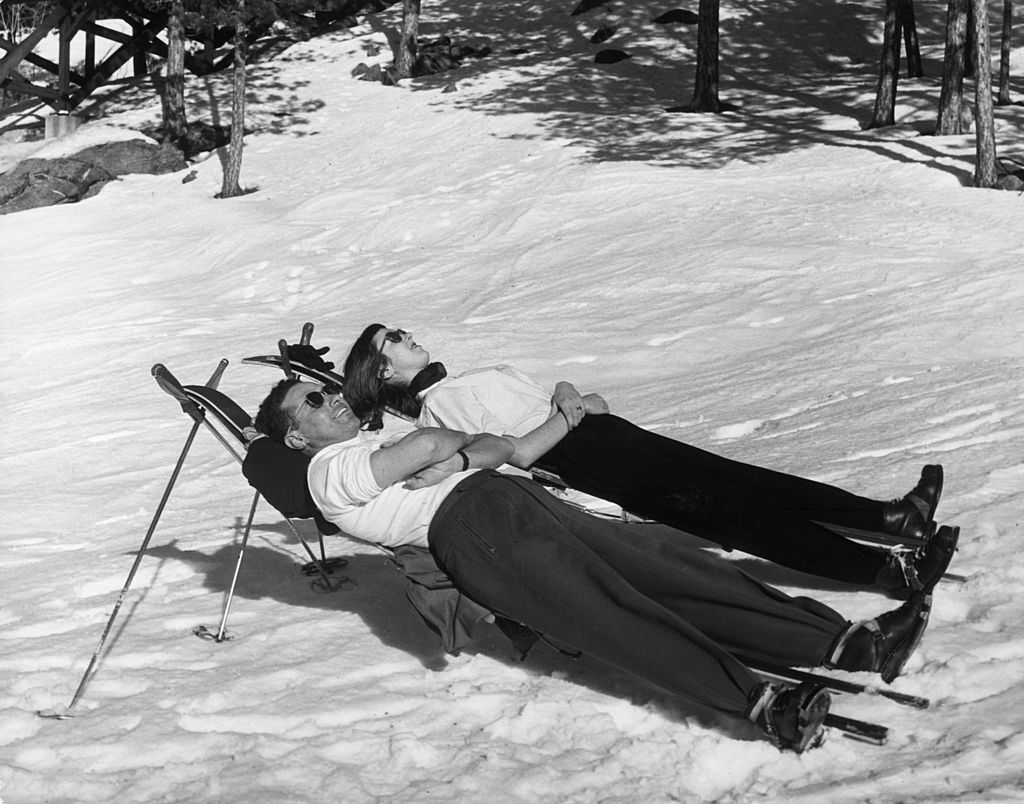 Couple enjoying sunbath in snow.