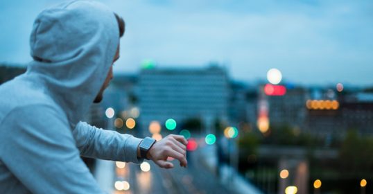 A man in a hoodie checking the time for his workout.