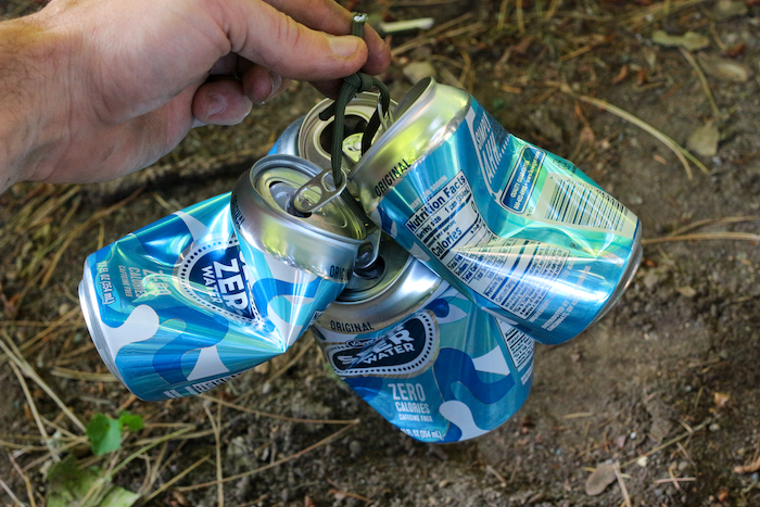 A man holding some empty cans with a sting.