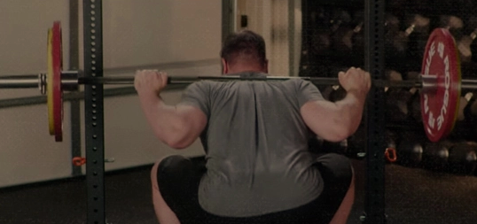 A man troubleshooting his squat form in the gym.