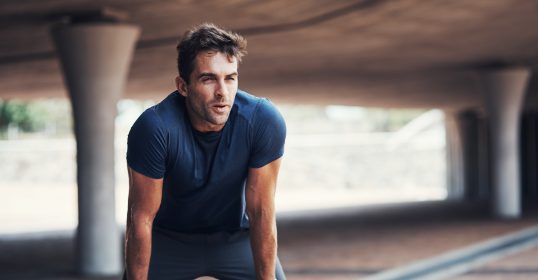 man with hands on knees breathing hard.