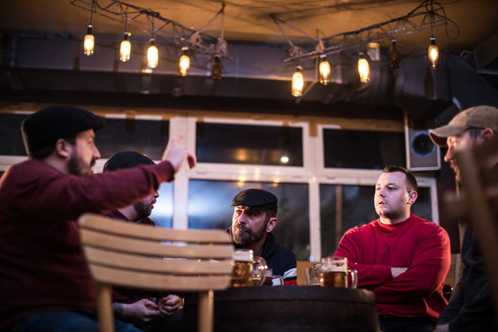 Group of adult men sitting in the bar drinking beer and talking.