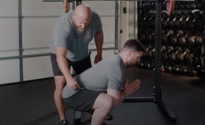 Gym instructor helping man while working out.