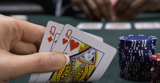 A person skillfully holding a pair of playing cards on a table.