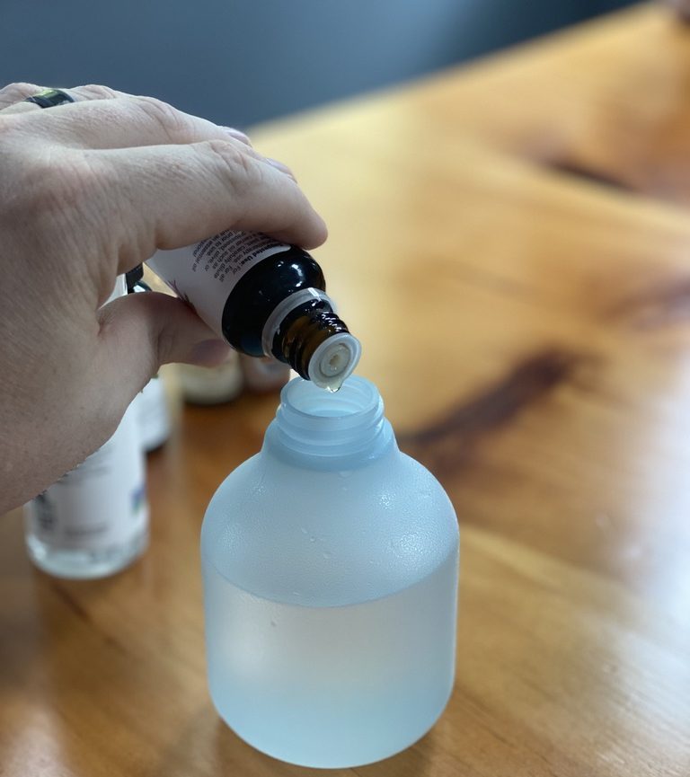 Essential oil being poured into spray bottle. 