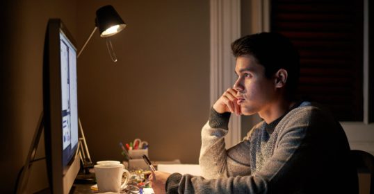 A young man overcoming challenges while working on his computer at night.