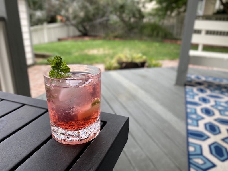 A pink drink on a table in front of a deck.