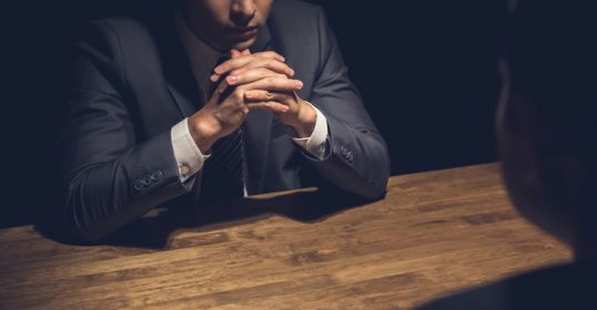 A businessman is building rapport with a woman at a table in a dark room.