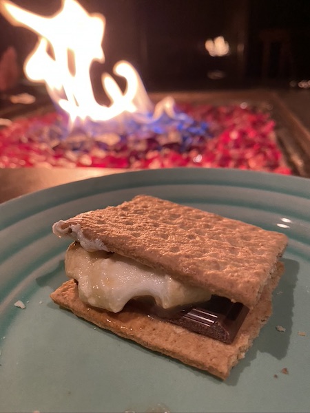 smore with marshmallow dipped in baileys and fire in the background. 