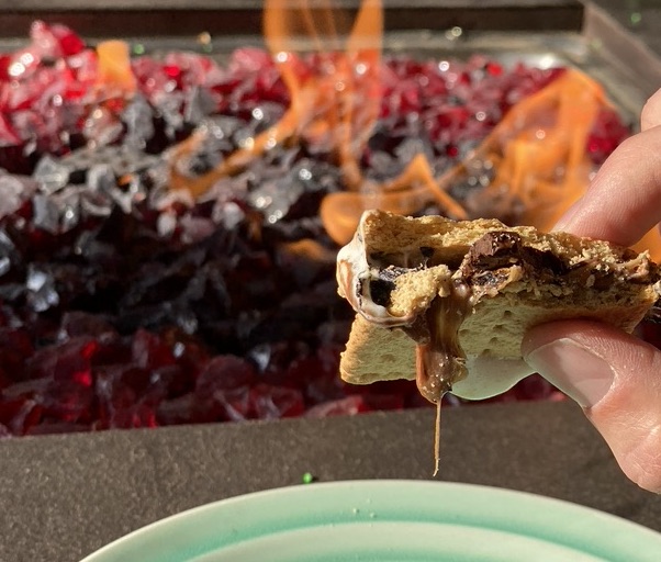 A person upgrading their s'more by the fire pit.