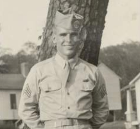 A man in uniform stands next to a tree, exuding steadiness and inspiration.