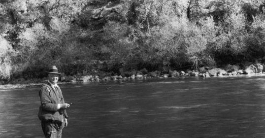 A man standing in a river with a fly rod enjoying some self-care.