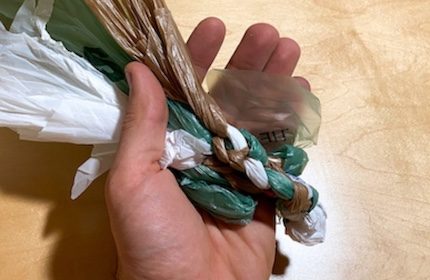 A hand holding a piece of plastic wrapped around a straw.