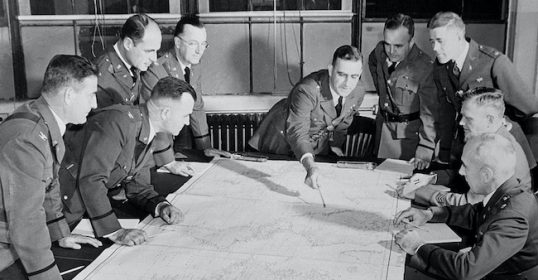 A group of military men in uniform consulting a map.