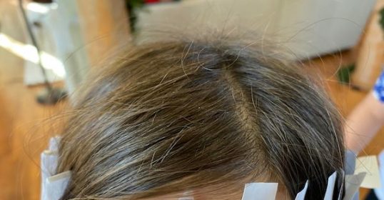 A little girl's head with paper taped to it, showing how inventive she is.