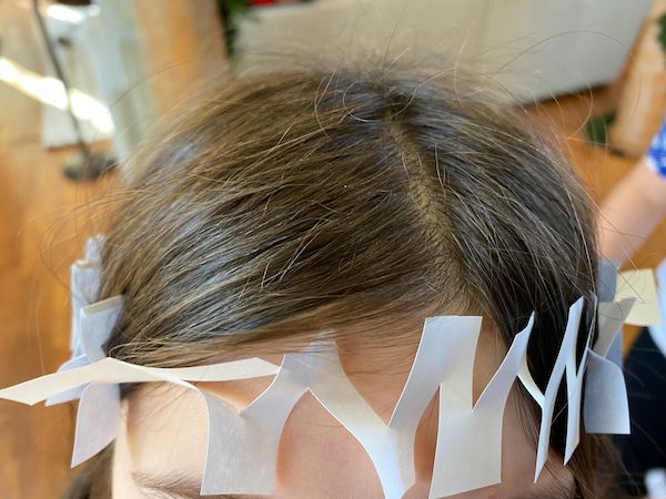 A little girl's head with paper taped to it, showing how inventive she is.