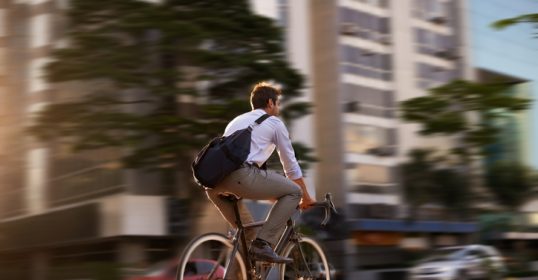 A man riding a bicycle on a city street during rush hour.