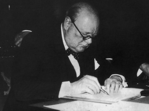 A man in a suit and tie signing a document for Sunday Firesides.