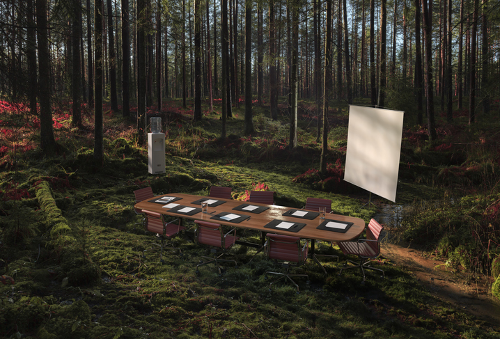 A table is set up in a forest with a projection screen for a podcast recording.