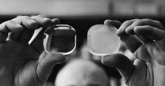 A man creates clarity by holding up two pieces of glass.