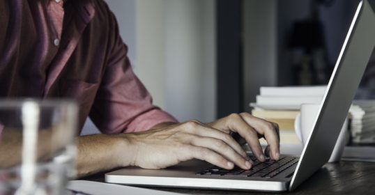 A man writing on a laptop.