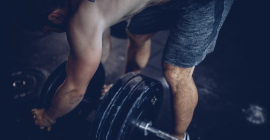 A man training with a barbell in the gym to build muscle.