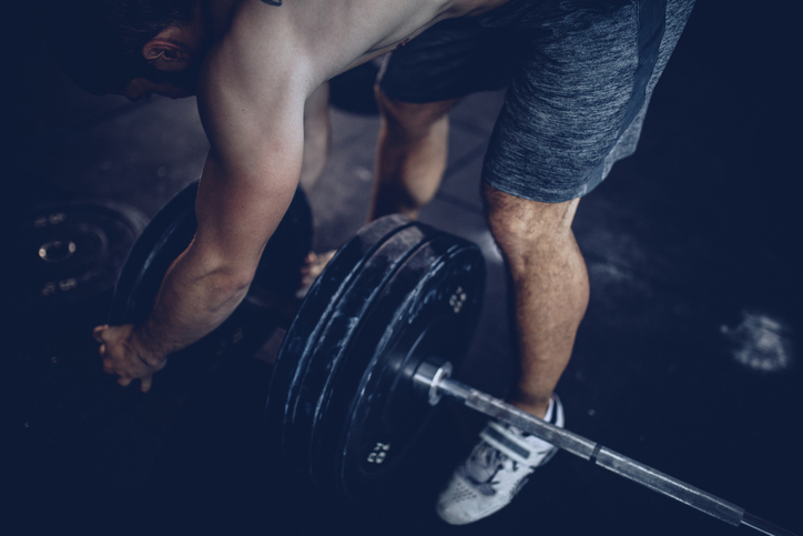 A man training with a barbell in the gym to build muscle.